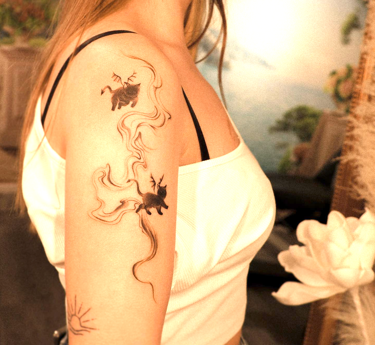 Zwei schwarze Katzen mit fließenden Linien als Oberarmtattoo