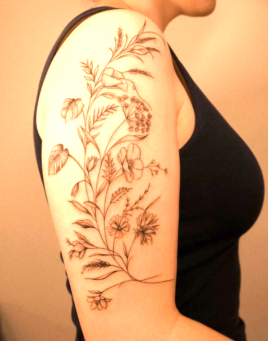 Großes botanisches Tattoo mit Wiesenblumen und Gräsern auf dem Oberarm